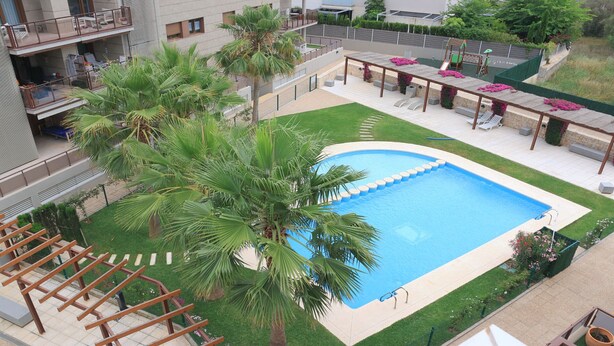 A rooftop pool with palm trees, a children's play area, and outdoor seating. - Apartamento Golden Star (Jávea)