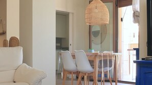 A modern living room with a wooden coffee table, a white sofa, and a dining area with a glass table and chairs. - Apartamento Golden Star (Jávea)