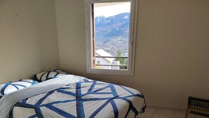 A bedroom with a bed, a window, and a view of a mountainous landscape. - Résidence Calme à Proximité Immédiate D'un Sentier de Randonnée (Embrun)