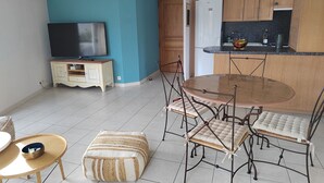 A compact living space with a dining area, kitchenette, and a television. - Résidence Calme à Proximité Immédiate D'un Sentier de Randonnée (Embrun)