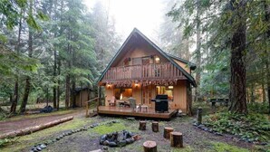 A cabin with a deck, surrounded by a forest. - Cozy Mt. Baker Cabin, Wi-Fi, Sleeps 6-8, Pets OK (Deming)