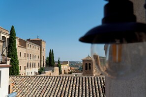 A view of a cityscape with terracotta-tiled rooftops, historic buildings, and a clear blue sky. - GRECO CERVANTES 5 COLLECTION (Toledo)