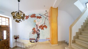 Una escalera con un mural, una puerta de madera y una lámpara de metal.