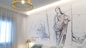 Un dormitorio con una cama grande, un mural en la pared, una ventana con cortinas ligeras y una lámpara de pie.
