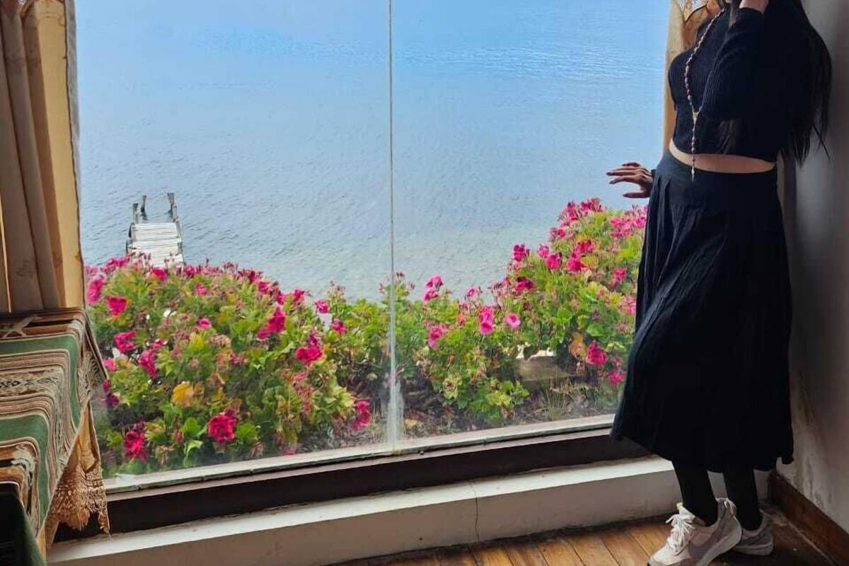 A room with a large window overlooking a body of water and distant mountains.