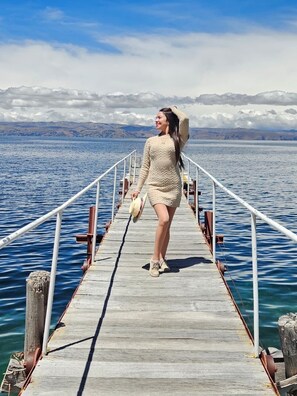 A wooden pier extending into a body of water with a mountainous landscape in the background. - LUNA DEL TITIKAKA LODGE (Moon Island)