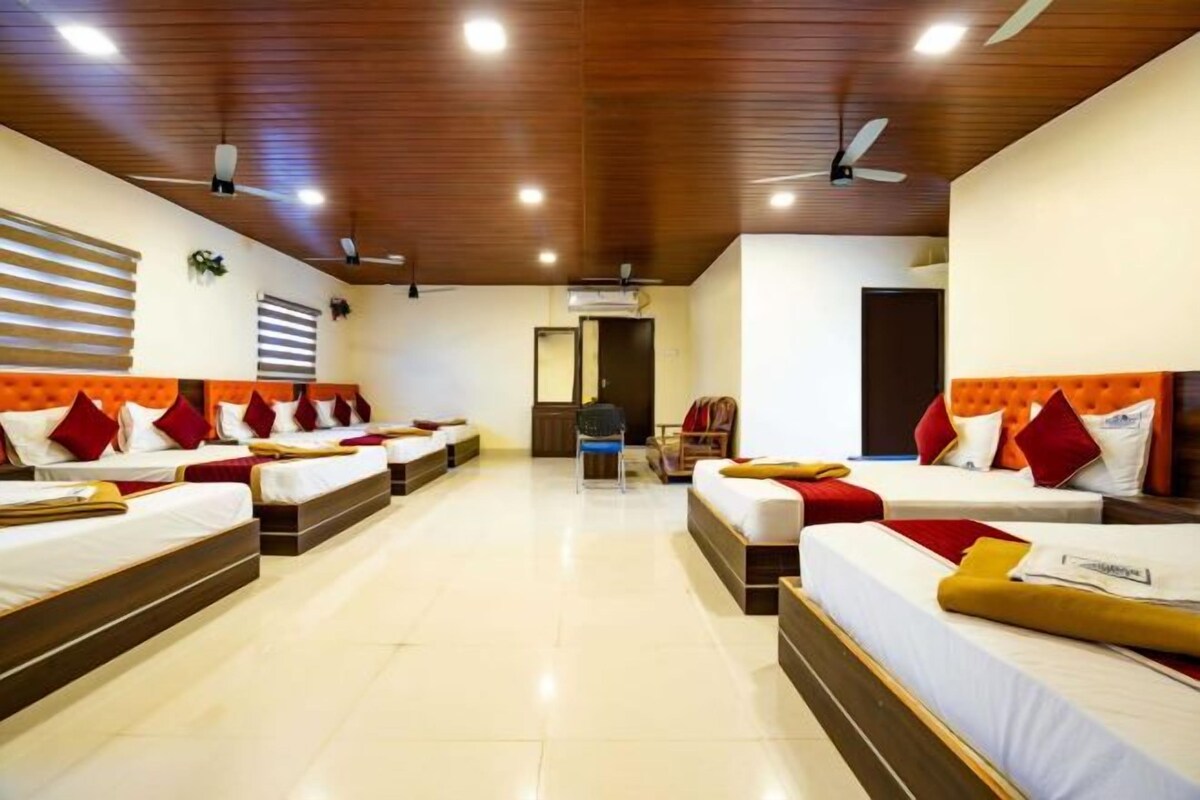 Une chambre d’hôtel avec plusieurs lits, un plafond en bois et un espace salon central.