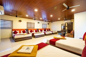 A hotel room with multiple beds, ceiling fans, and a mirror. - Sree Kumaran Residence by Royal stay (Rameshwaram)