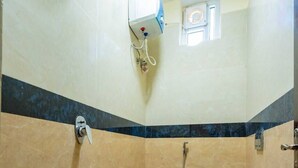 Pieni kylpyhuone, jossa on wc, suihku ja seinälle asennettu ilmastointilaite.