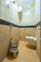Un baño pequeño con inodoro, ducha y aire acondicionado de pared.