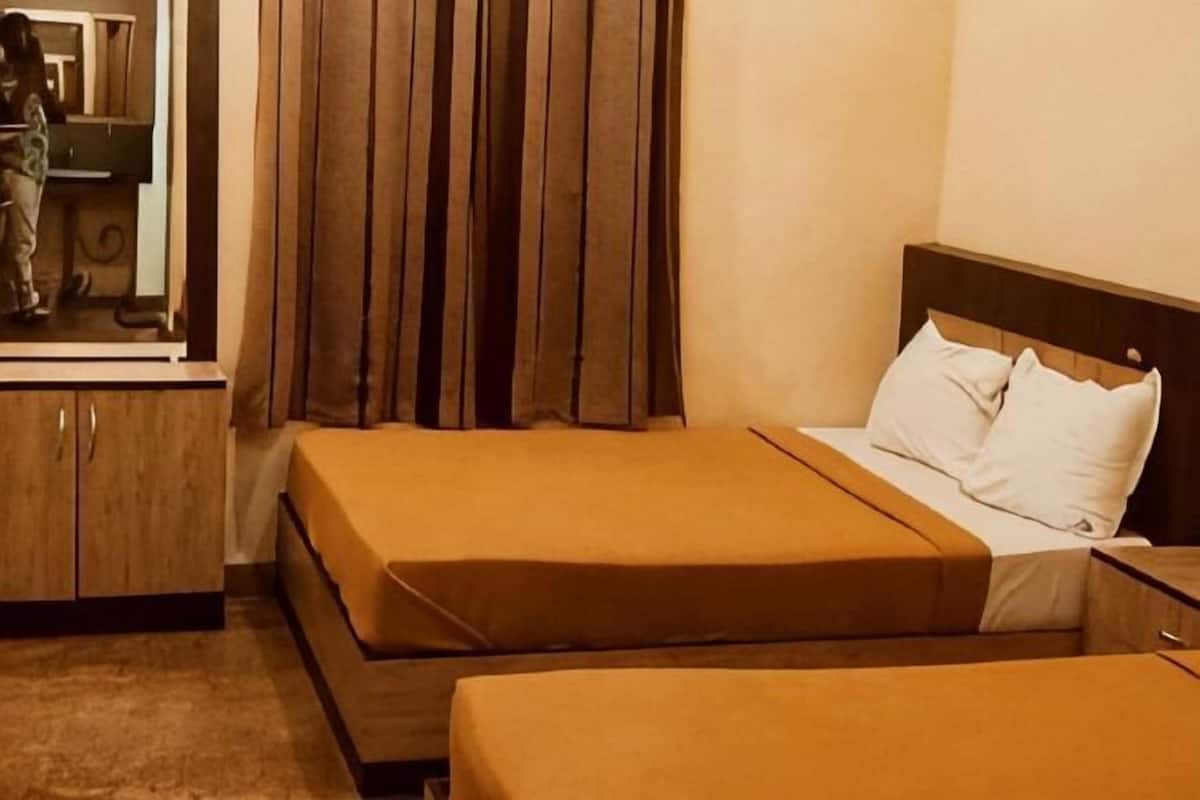 Ein Hotelzimmer mit zwei Betten, einem hölzernen Kopfteil, einem Spiegel und einem Kleiderschrank.