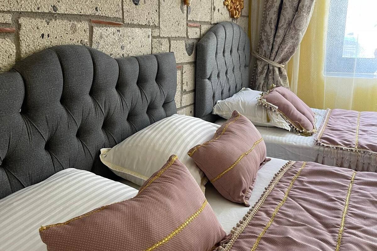 A bedroom with a tufted headboard, a large mirror, and decorative wall sconces.