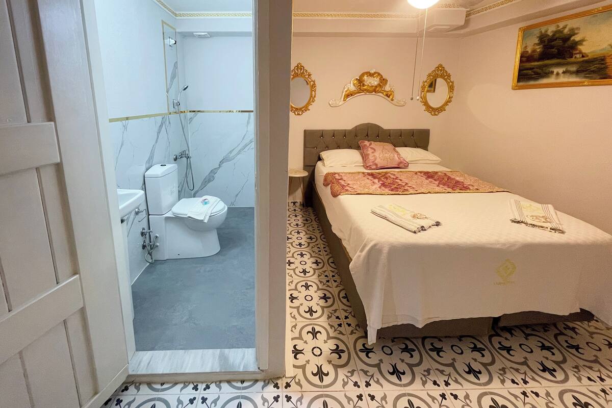 A hotel room with a bed, a bathroom with a toilet and shower, and a ceiling fan.