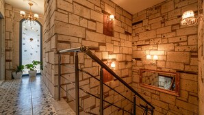 A staircase with a metal handrail, a wall with a large mirror, and a decorative chandelier. - Lamur Otel (Cesme)
