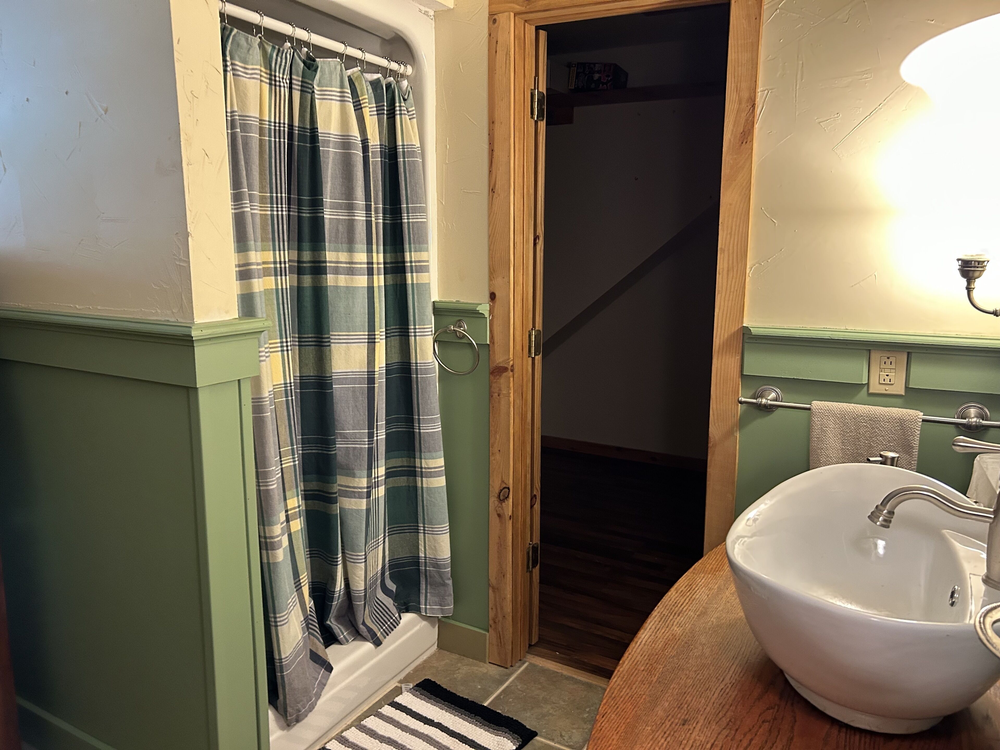 A bathroom with a green and white color scheme, a white sink, and a shower curtain.
