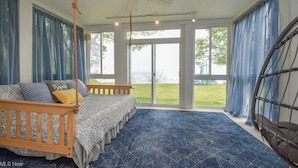 Ein Schlafzimmer mit einem großen Bett, einem Deckenventilator und Blick auf eine Rasenfläche durch die Glastüren.