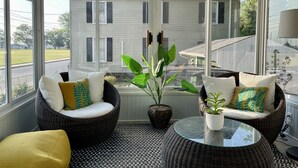A sunroom with wicker furniture, a glass table, and a view of a house. - New listing! Riverside Retreat on the Choptank River (Cambridge)