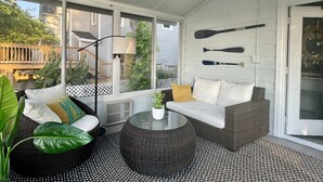 A sunroom with wicker furniture, a ceiling fan, and large windows overlooking a deck. - New listing! Riverside Retreat on the Choptank River (Cambridge)
