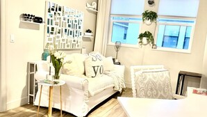 A living room with a sofa, a coffee table, a dining table, and a ceiling fan.