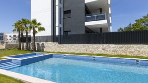 Un edificio moderno con piscina, pared de piedra y palmeras.