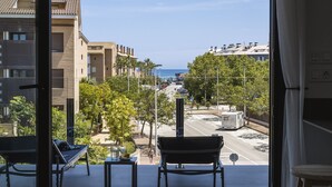 Un balcón con vistas a la calle, edificios y el mar.
