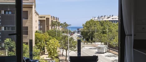A balcony with a view of a street, buildings, and the sea.