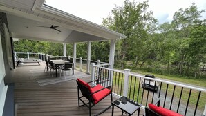 A covered outdoor deck with a table and chairs, a small table with a chair, and a railing. - River Perch on the Cacapon: private home on 27 acres and 1200 ft of riverfront (Yellow Spring)