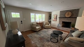 A living room with a fireplace, two armchairs, a sofa, a coffee table, and a rug. - River Perch on the Cacapon: private home on 27 acres and 1200 ft of riverfront (Yellow Spring)