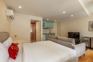 Ein Hotelzimmer mit Bett, einer Couch, einem Fernseher, einem Schreibtisch und einer Küchenzeile.