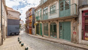 A narrow cobblestone street lined with historic buildings, featuring balconies, green doors, and a mix of architectural styles. - Dasi Estudio C boutique apartment (Oporto)
