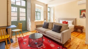 A modern living room with a sofa, a coffee table, and a chair. There is a door leading to a balcony. - Dasi Estudio C boutique apartment (Oporto)