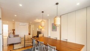A modern dining area with a wooden table, white chairs, and pendant lighting.