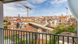 A balcony with a view of a cityscape, including buildings and a construction crane.