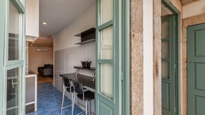 Une cuisine compacte avec un coin repas, comprenant une petite table et des chaises, un four encastré et une fenêtre à vitre dépolie.