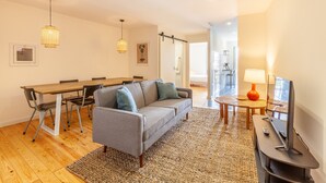Un salon moderne comprenant un canapé, une table à manger, des chaises et un téléviseur.