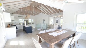 Een ruime keuken met een centraal eiland, een eetgedeelte met een houten tafel, en een woonruimte met een bank en een televisie.