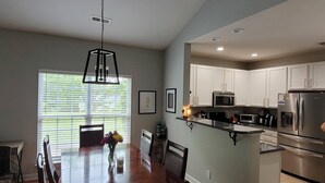 A modern kitchen with white cabinets, stainless steel appliances, and a dining area with a wooden table and chairs. - Comfortable, covenient, quaint (Winston-Salem)