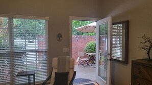 A bedroom with a bed, a chair, a small table, and a door leading to an outdoor patio with a table and chairs. - Comfortable, covenient, quaint (Winston-Salem)