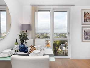 Enjoy meals in this stylish dining area with a table for four, a beautiful view of the city, and elegant artwork on the walls.