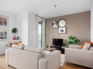 Relax in this stylish living room with a sofa, armchair, and flat-screen TV.