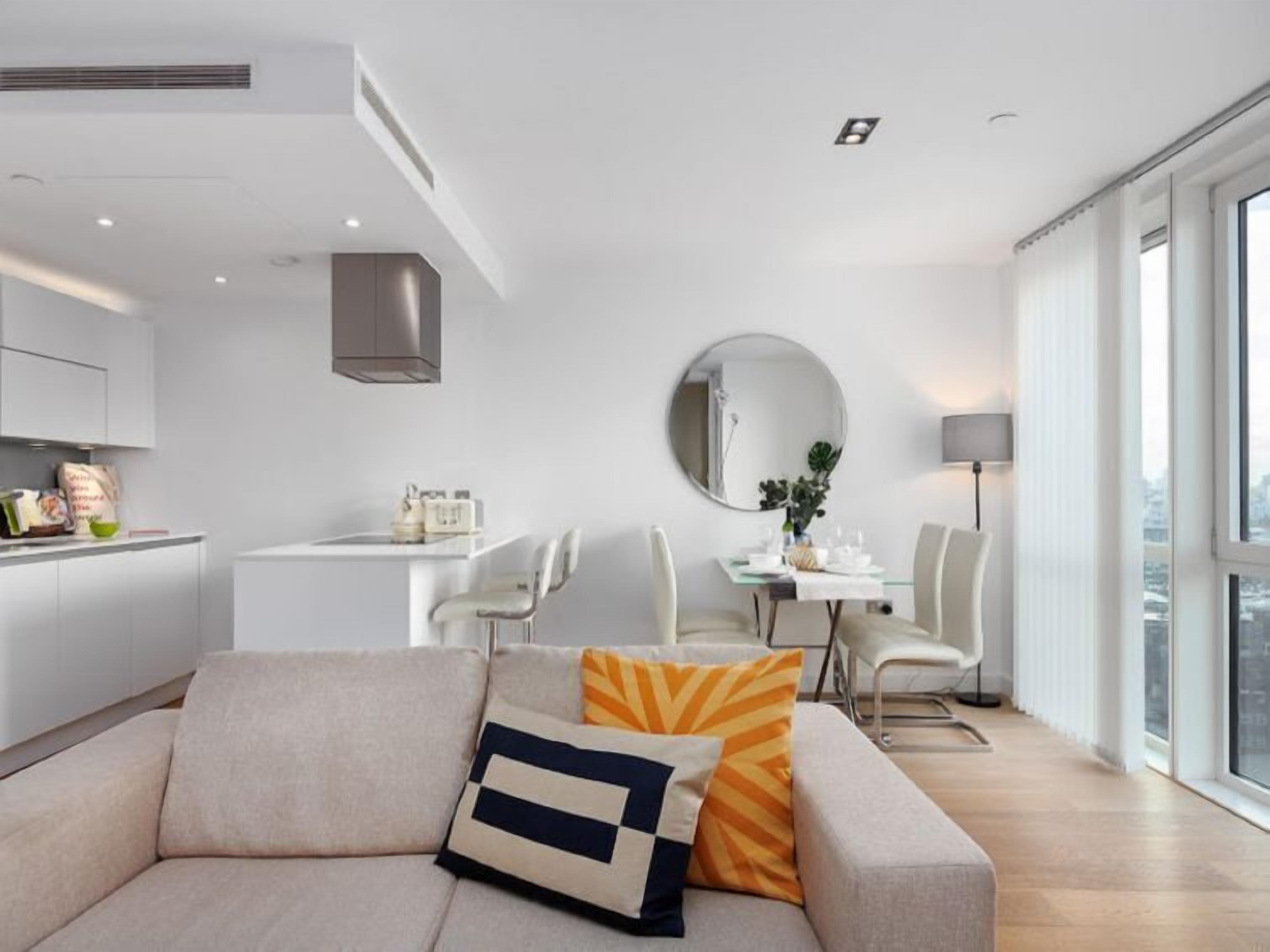Una sala moderna con un sofá, una mesa de comedor y una zona de cocina.