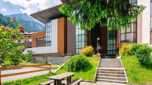 A modern building with large windows, a stone staircase, and a picnic table in a landscaped garden. - Appartamento Antermoia by Interhome (Canazei)