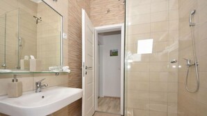 A modern bathroom with a glass shower enclosure, a white sink with a mirror, and a door leading to another room. - Zalazak Sunca by Interhome (Novigrad (Zadar))