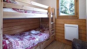 Una camera con un letto a castello, una finestra e un termosifone.