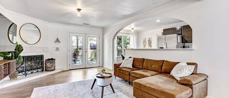 A spacious living room with a brown leather sofa, a round coffee table, and a large rug.