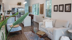 A spacious living area with a sofa, a coffee table, and a dining area with a kitchen in the background. - Delightful Cottage in Historic Downtown St. Augustine Florida (St. Augustine)