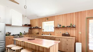 A modern kitchen with wooden paneling, a central island with stools, and built-in appliances.