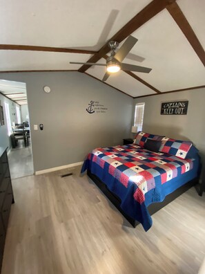 Une chambre avec un lit, un ventilateur de plafond, un mur décoré d’un motif sur le thème de la marine, et une pancarte indiquant : « CAPITAINE, DÉFENSE D’ENTRER ».