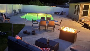 Un jardin avec une piscine, du mobilier d’extérieur et un foyer.