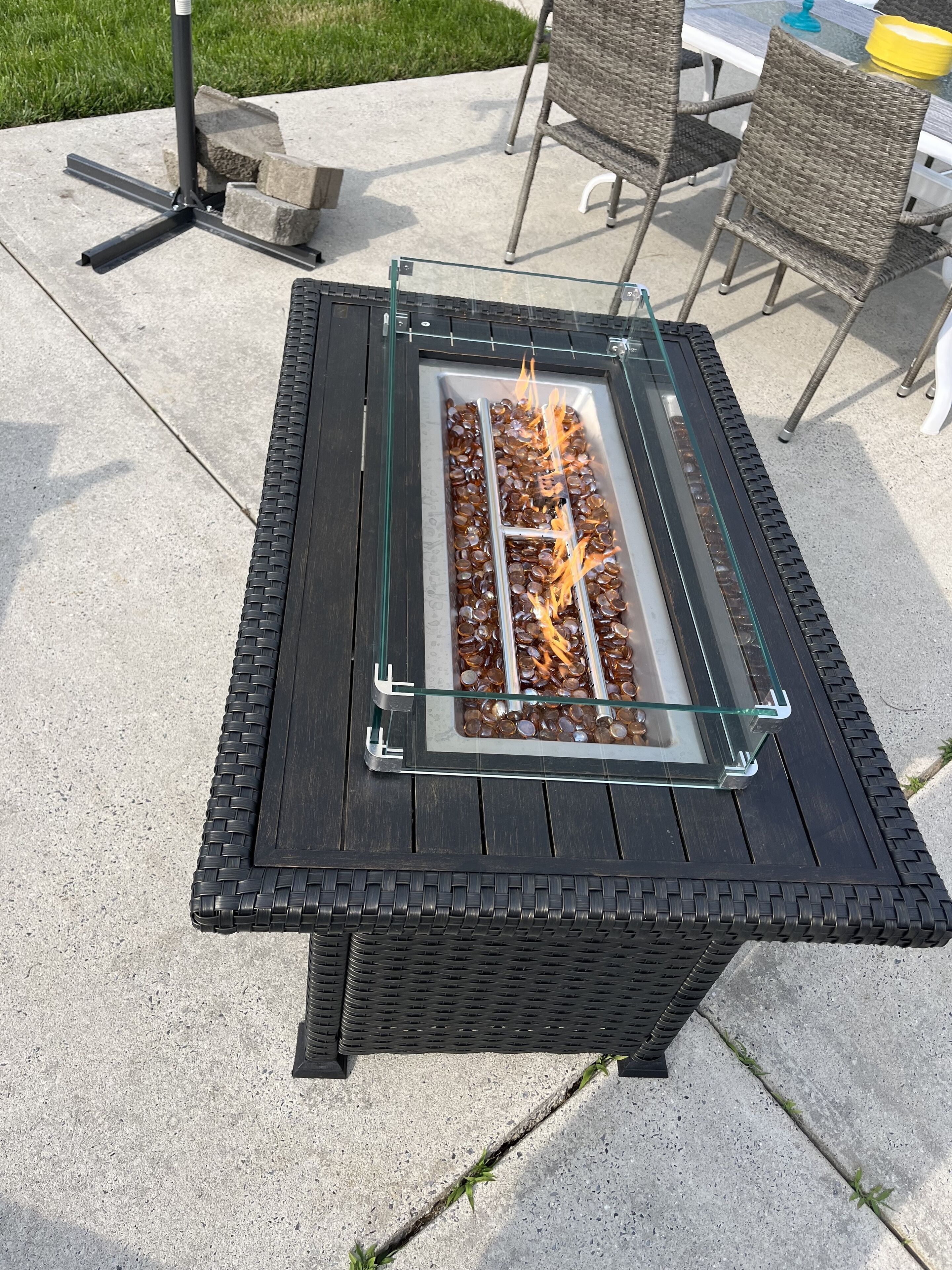 Una mesa exterior cuadrada con una estructura de cristal y una chimenea integrada.